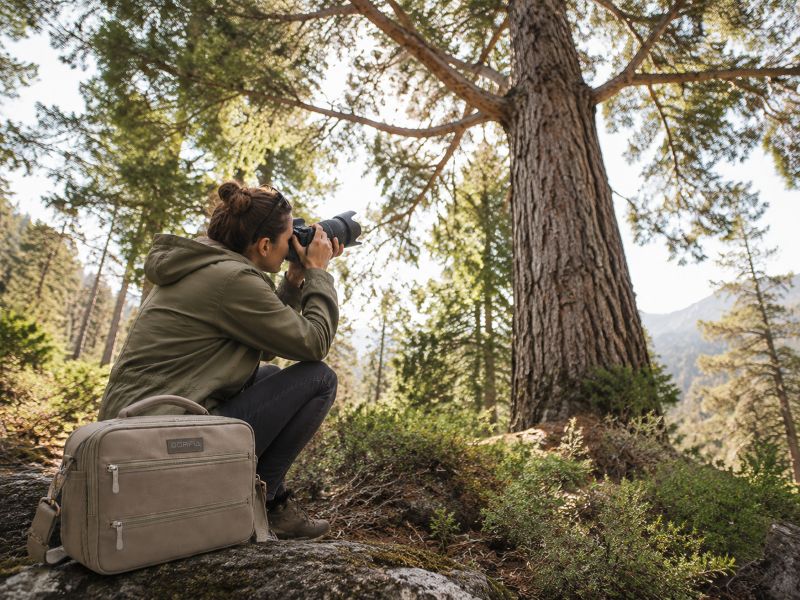 a-woman-is-shooting-a-tree-beside-a-camera-bag