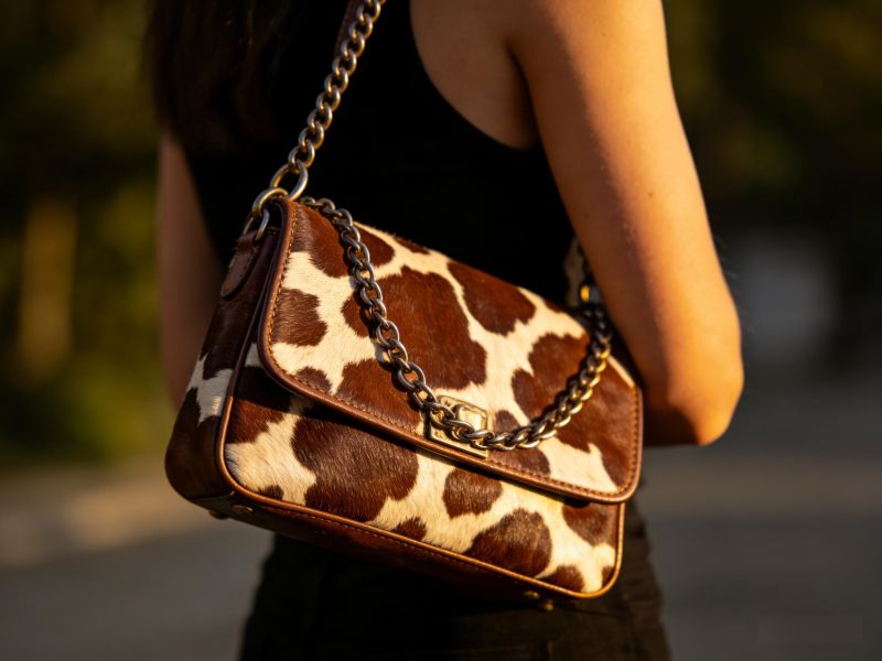 cow-print-hobo-bag-with-gorfia-branding-held-by-woman-on-parisian-street