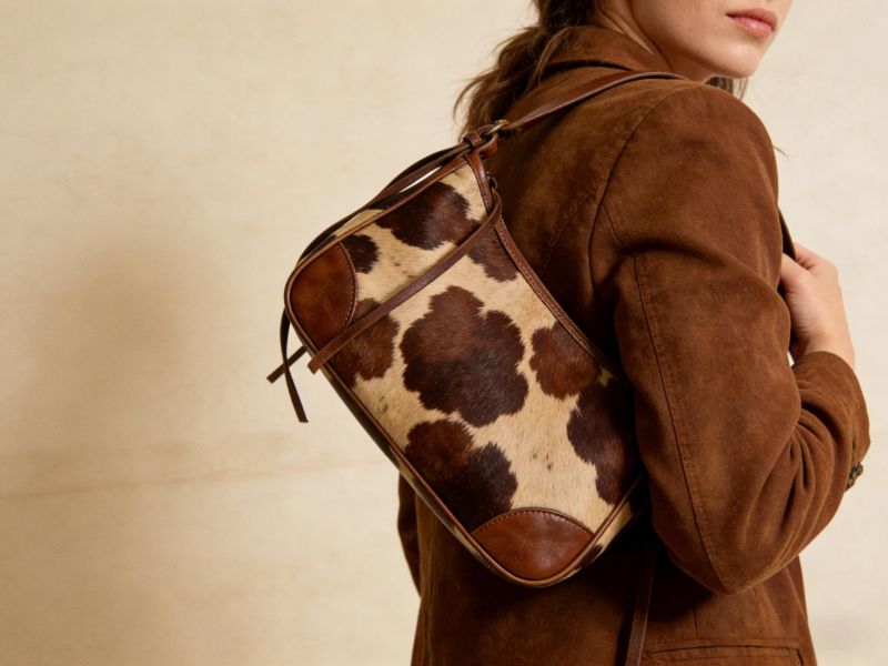 brown-cow-print-leather-bag-carried-by-woman-in-brown-jacket