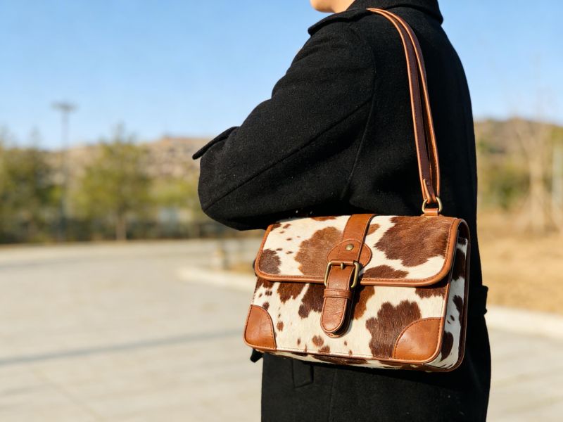 brown-cow-print-shoulder-bag-carried-by-person-in-black-coat